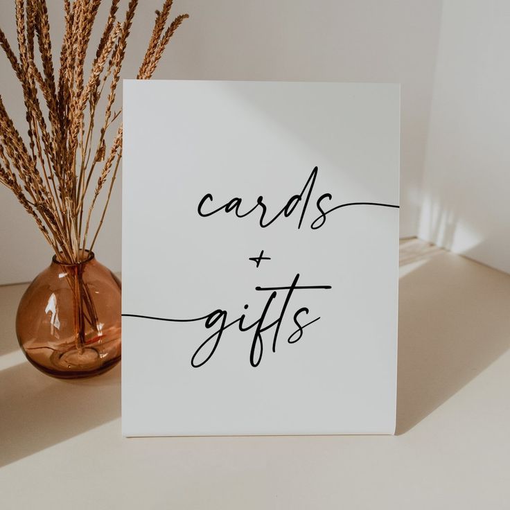 a card that says cards and gifts next to a vase with dry grass in it