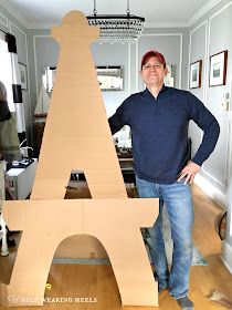 a man standing next to a cardboard model of the eiffel tower