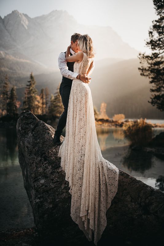 a man and woman standing on top of a rock