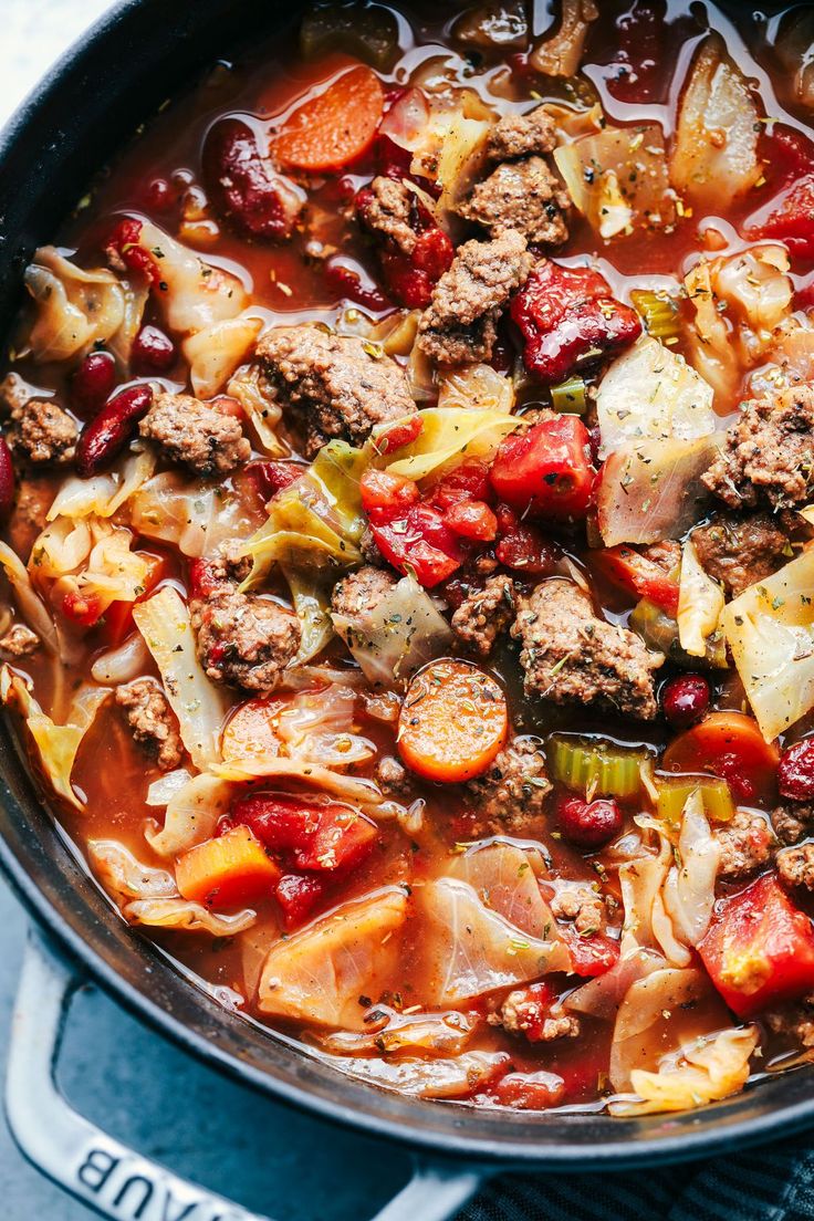 a pot filled with meat and vegetables on top of a stove next to a spoon