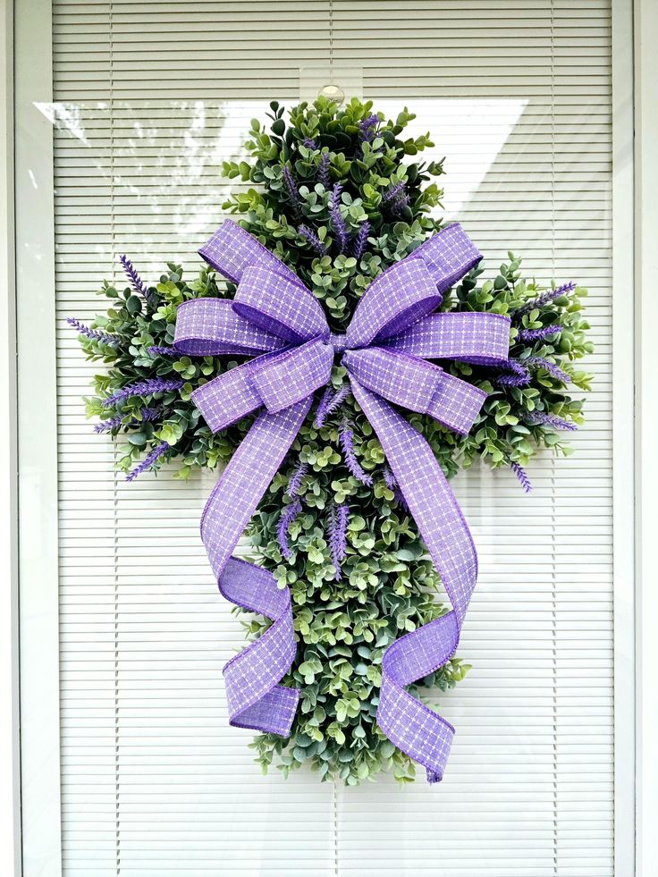 a wreath with purple bows hanging on the front door