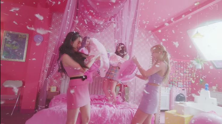 two girls in pink dresses are playing with barbie dolls and confetti on the bed