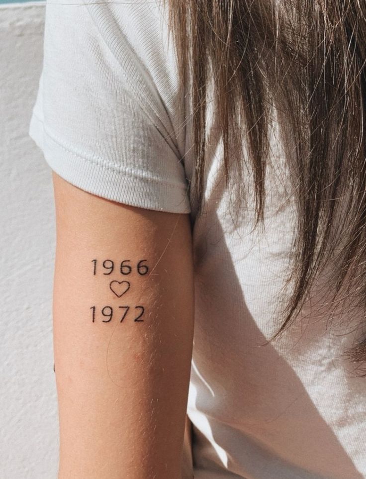 a woman with a tattoo on her arm that reads 1956 and has hearts in it