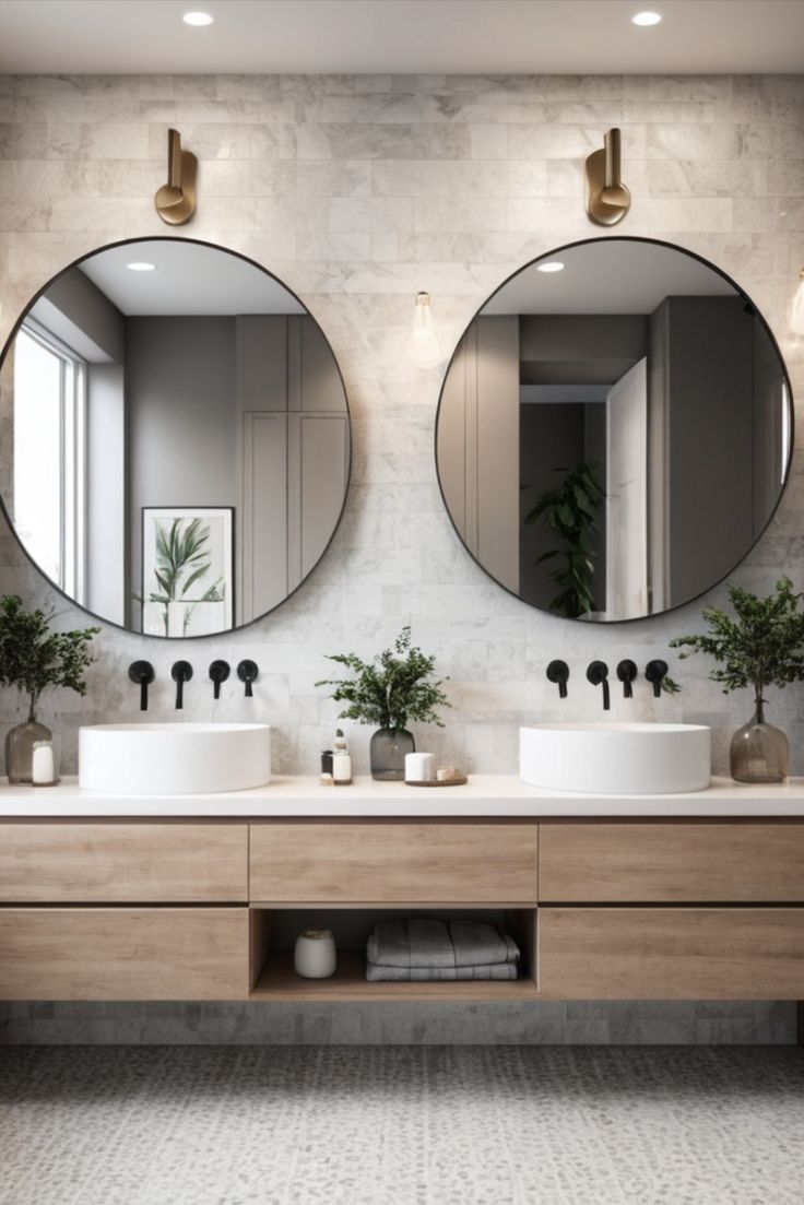 two round mirrors are above the double sinks in this modern bathroom with marble walls and flooring