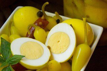 a white bowl filled with yellow fruit and sliced egg halves on top of each other