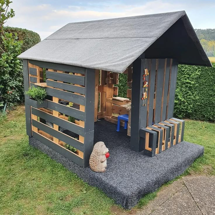 a small wooden shed with a sheep statue in the yard