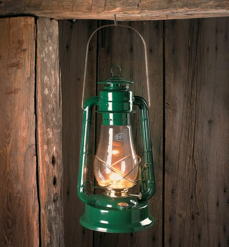 a green lantern hanging from the side of a wooden wall