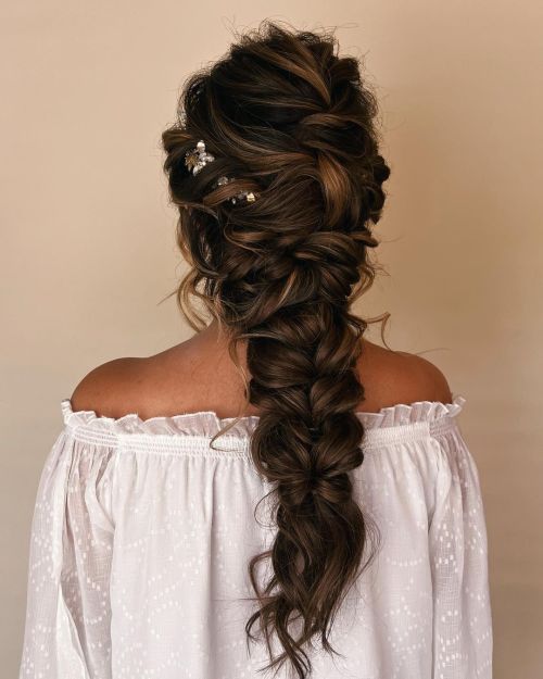 a woman with long hair wearing a white blouse and braid in her hair, looking off to the side