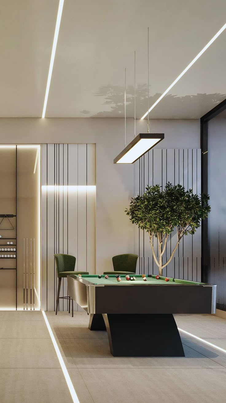 a pool table in the middle of a room with two chairs and a potted plant