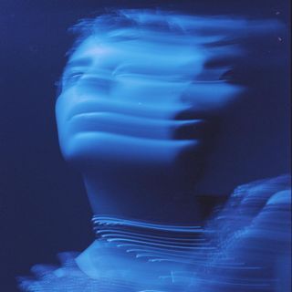 a blurry photo of a woman's face with blue light in the background