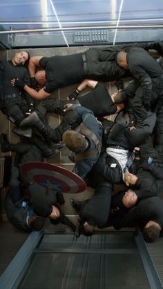 a group of men laying on top of each other in front of an escalator