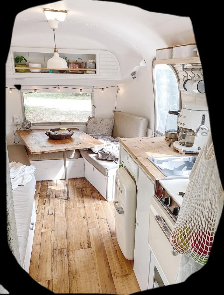 the interior of a camper with wood floors and white appliances, including a stove top oven