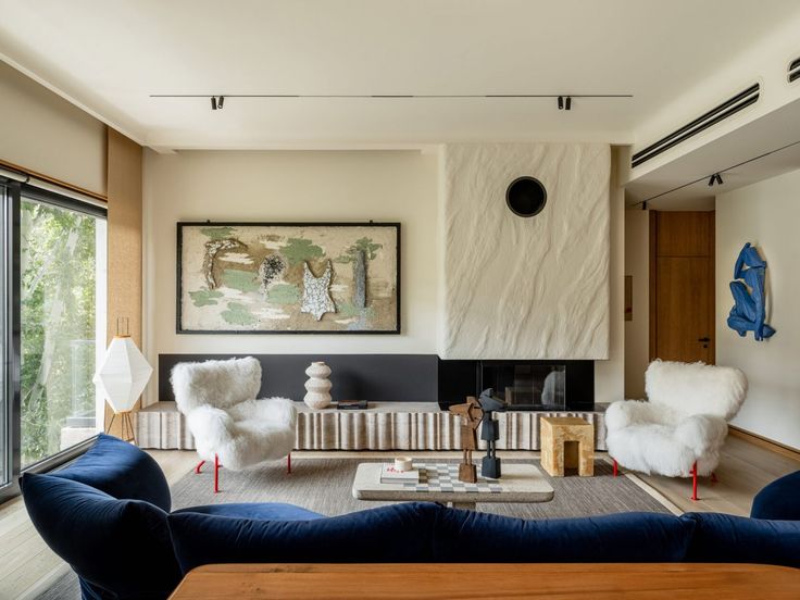 a living room filled with furniture and a painting on the wall above it's fireplace