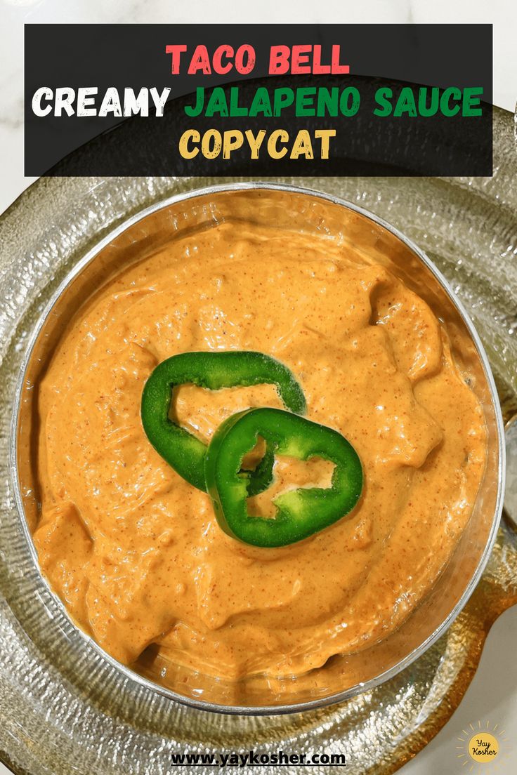 a metal bowl filled with creamy jalapeno sauce next to a green pepper