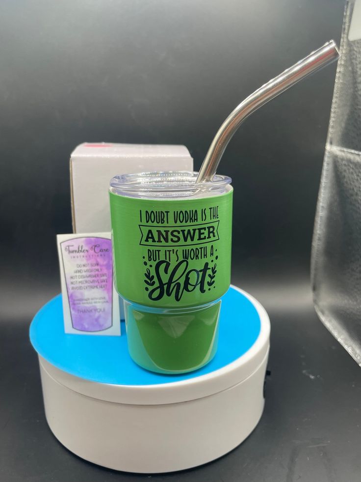 a green cup with a spoon in it on a blue stand next to some boxes