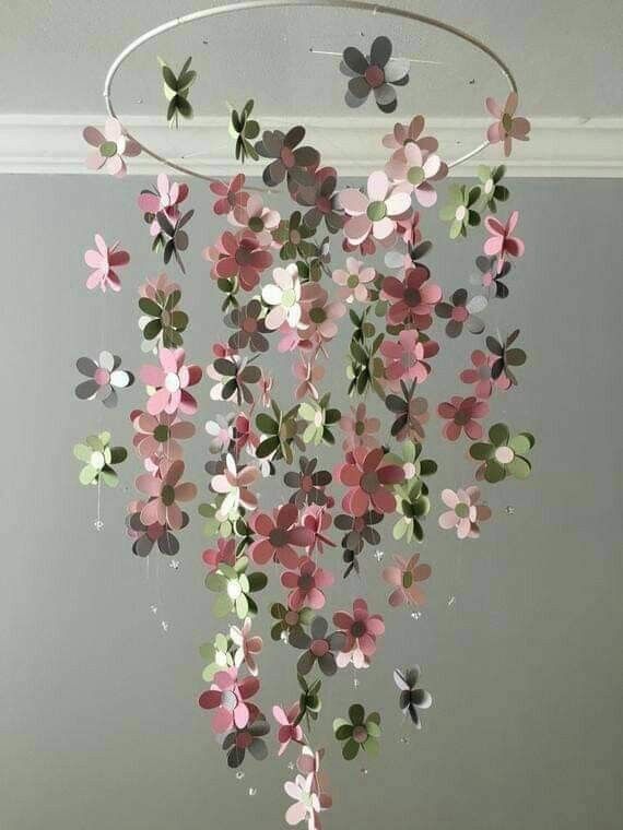 some pink and green paper flowers hanging from a ceiling