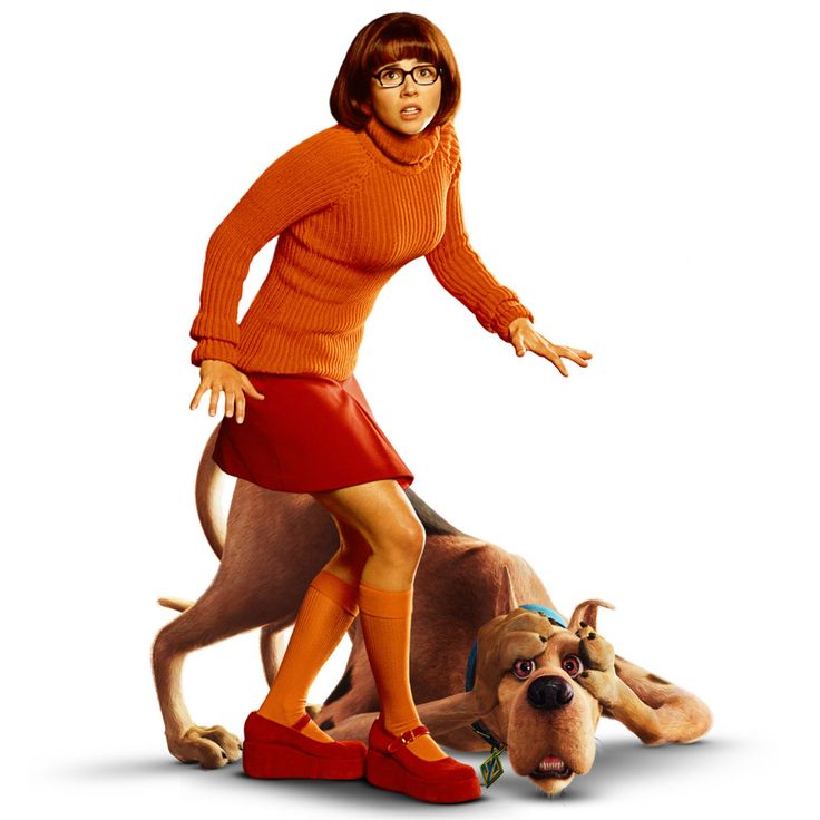 a woman in an orange sweater and red shoes standing next to a dog