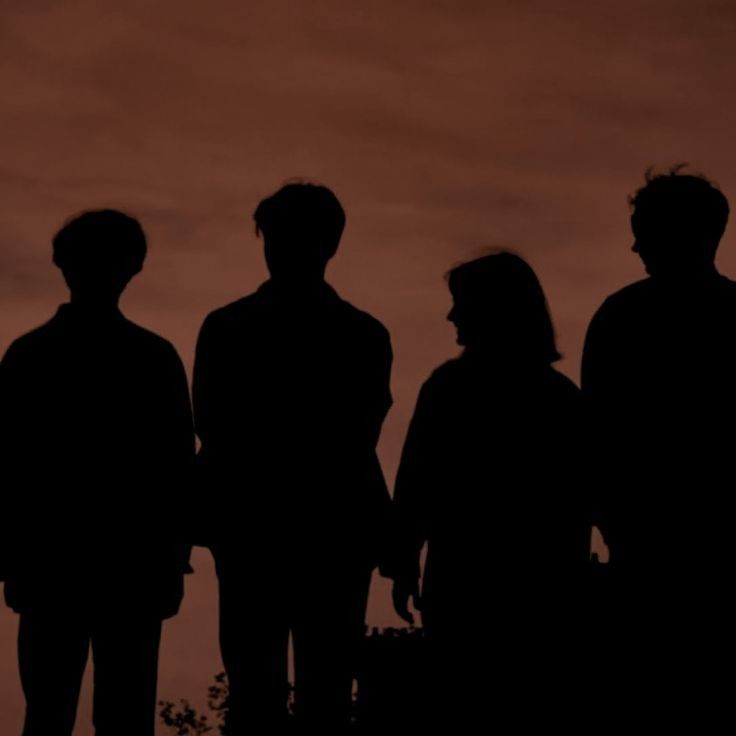 the silhouettes of three people standing next to each other in front of an orange sky