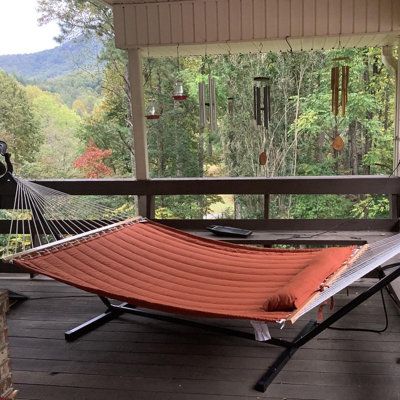 an orange hammock sitting on top of a wooden deck