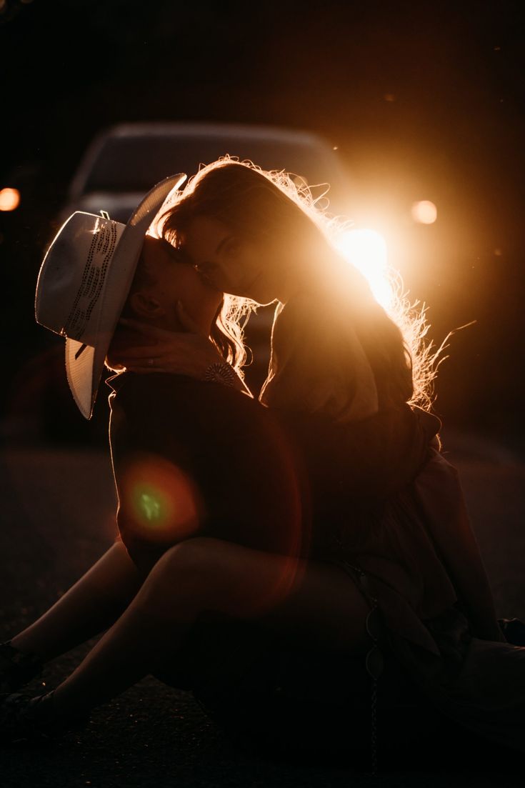 a woman sitting on the ground with her head turned to the side and light shining behind her