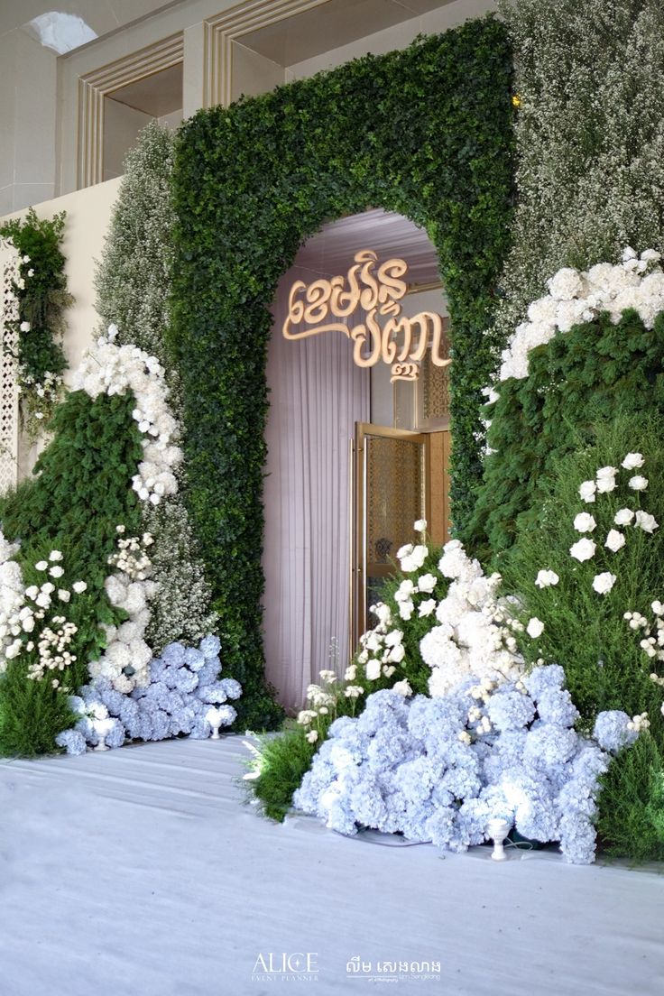 the entrance to an event decorated with flowers and greenery