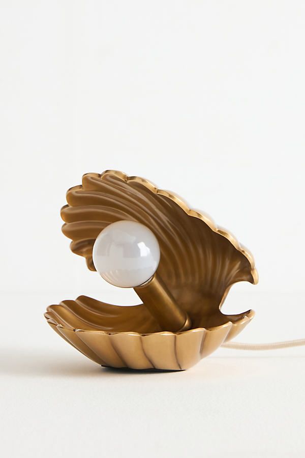 a golden shell lamp with a white ball in it's center, on a white background