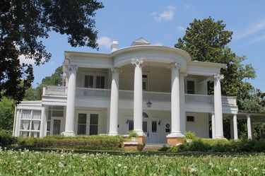 a large white house sitting on top of a lush green field