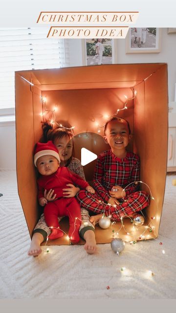 two children sitting in a cardboard box with christmas lights