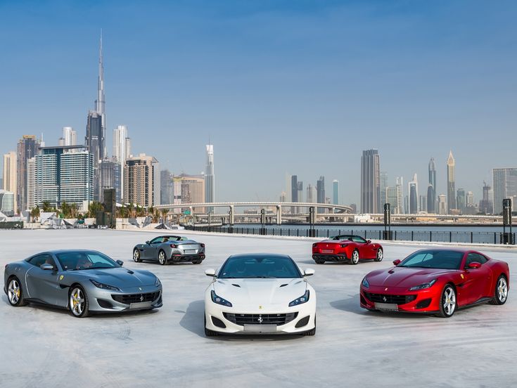 four different colored sports cars in front of a city skyline