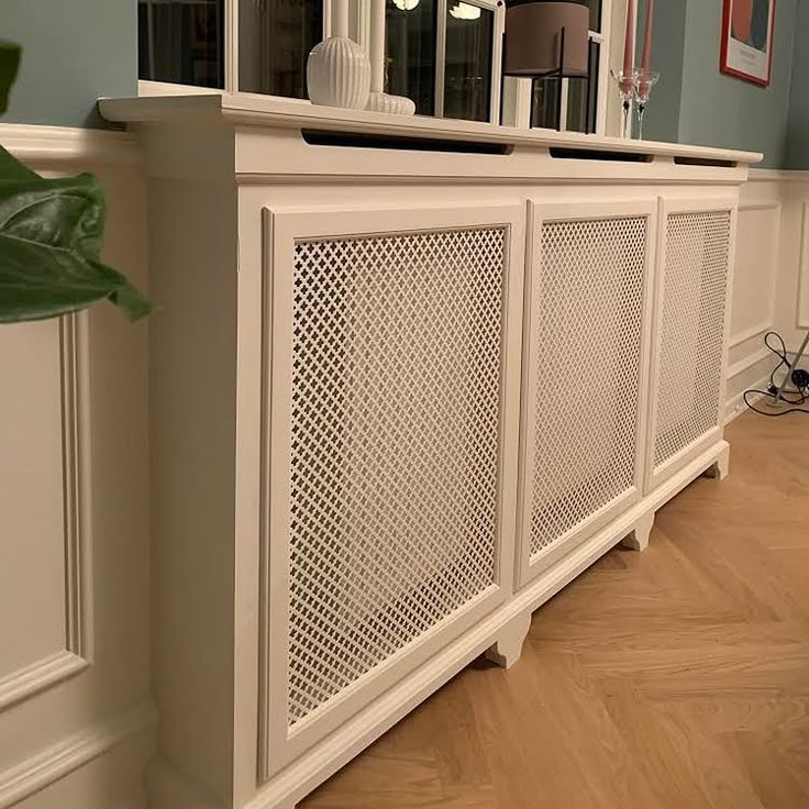 a large white cabinet sitting in the corner of a room next to a wall with pictures on it