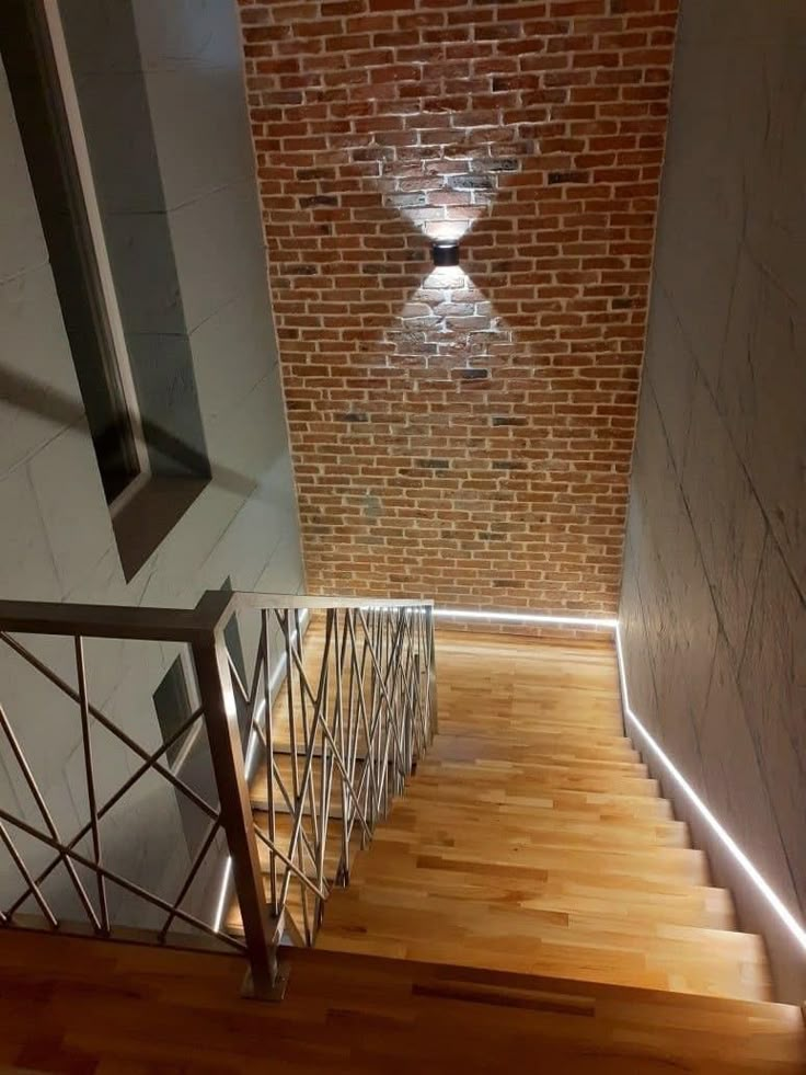 the stairs are made of wood and have metal handrails on them, along with a brick wall in the background