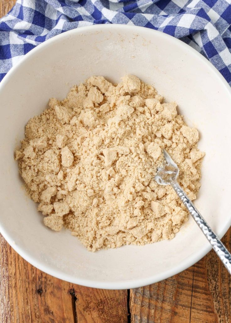 a white bowl filled with oatmeal next to a blue and white checkered napkin