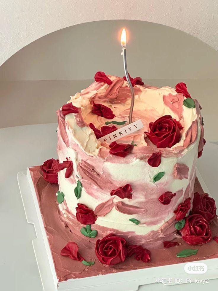 a birthday cake decorated with roses and a single candle