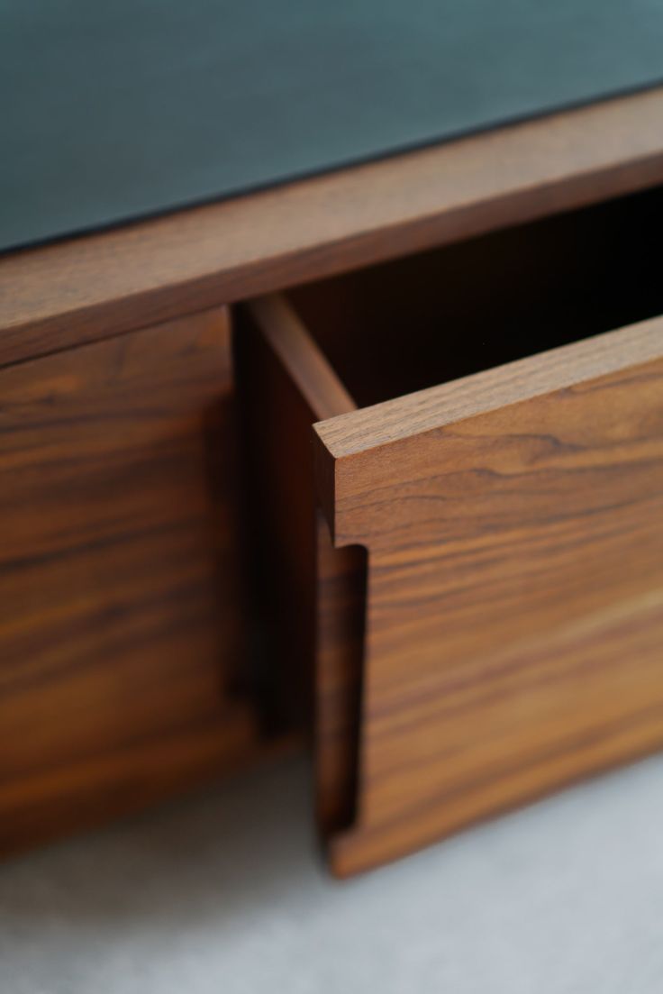 a close up view of a wooden desk with two drawers on one side and an open drawer on the other