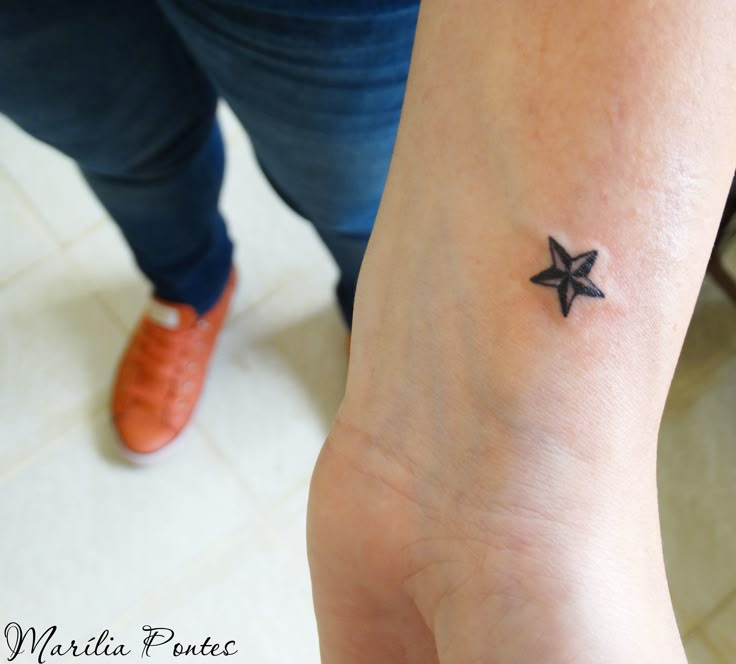 a person with a small star tattoo on their wrist