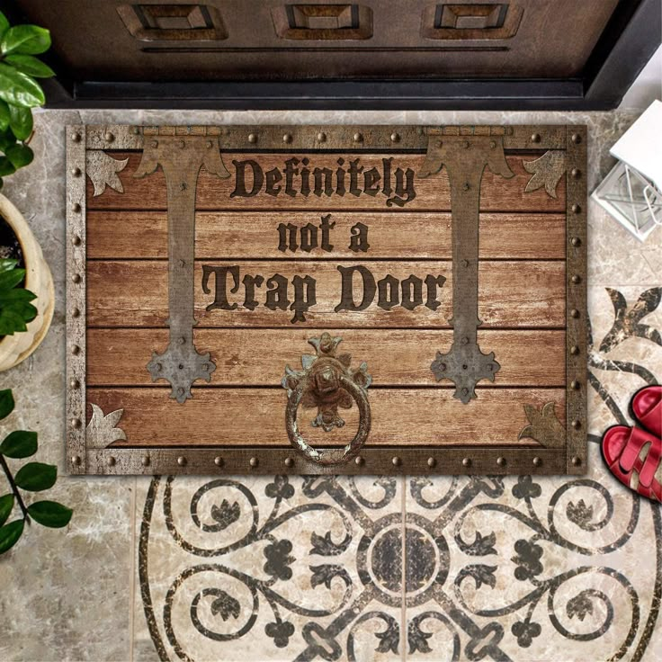 a door mat that says definitely not a trap door on the floor next to a potted plant