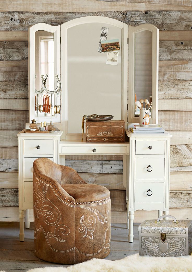 a chair sitting in front of a white desk with a mirror on top of it