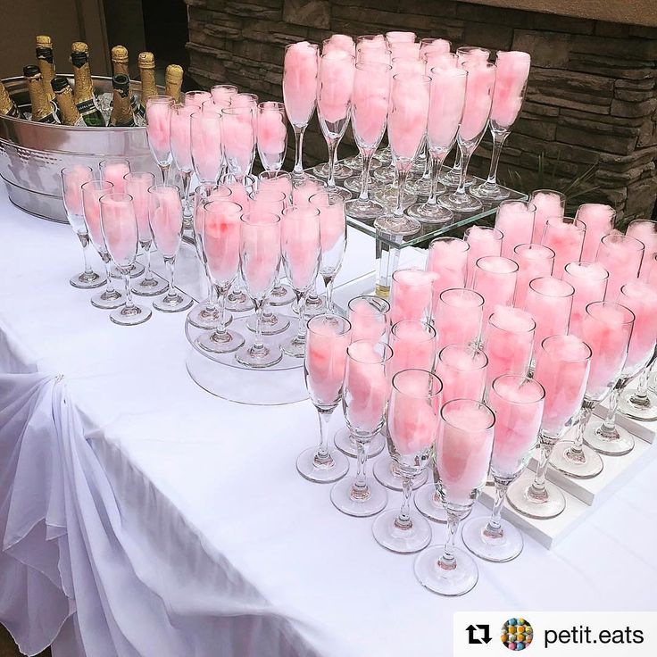 a table topped with lots of wine glasses filled with pink liquid sitting on top of each other