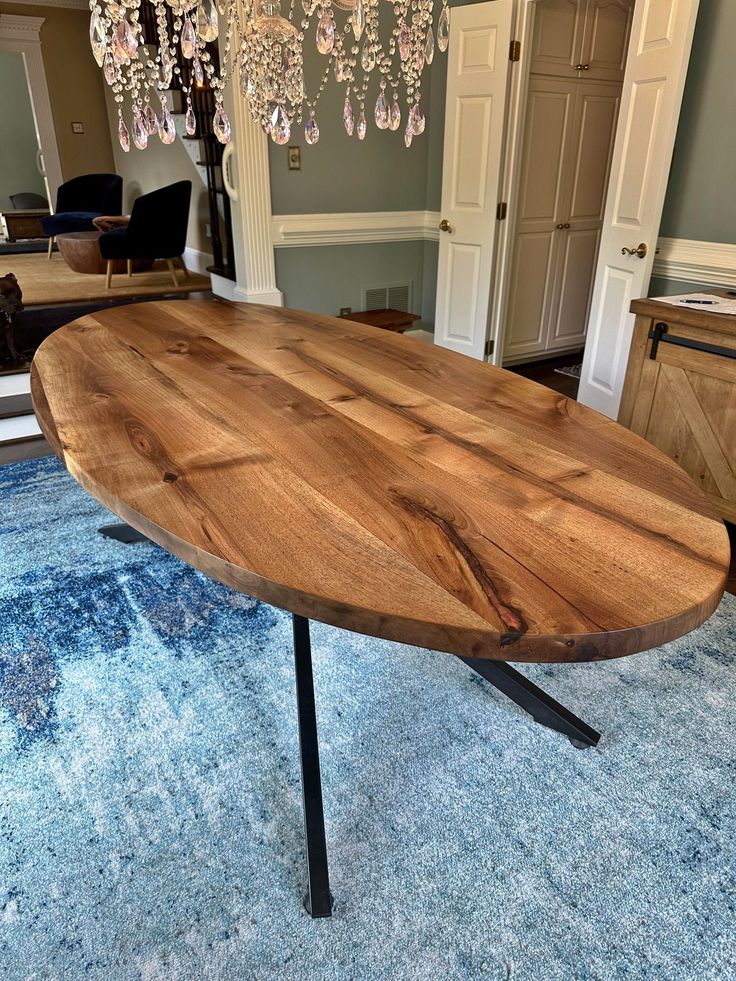 a wooden table sitting on top of a blue rug in front of a chandelier