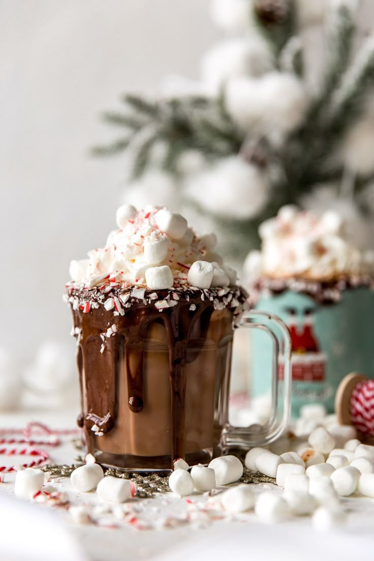 two mugs filled with hot chocolate and marshmallows on top of a table