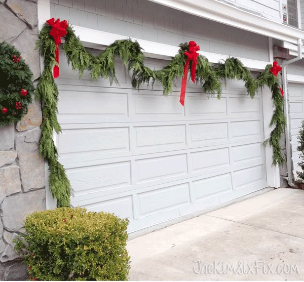 a garage decorated for christmas with greenery and red bows