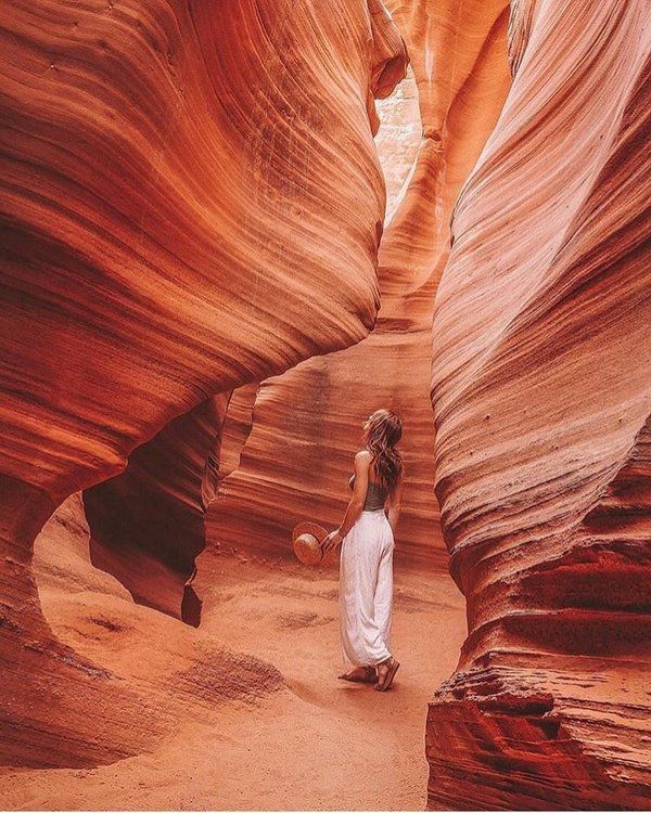 a woman standing in the middle of a canyon