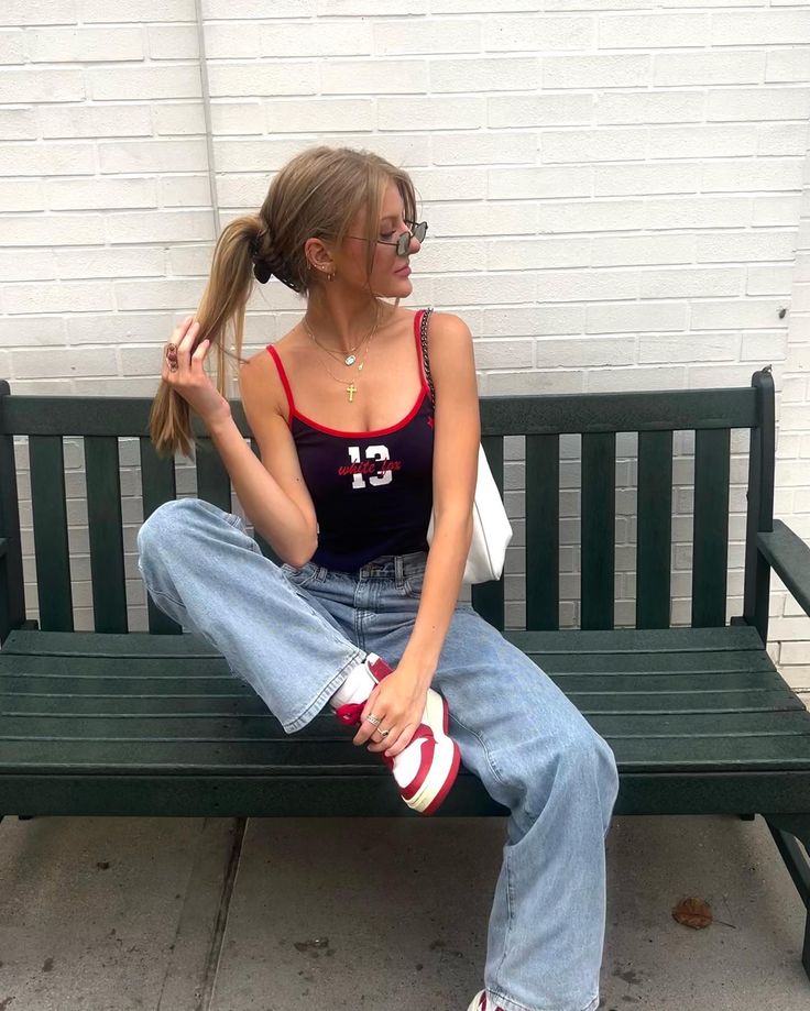 a woman sitting on a bench with her hair in a pony tail and red shoes