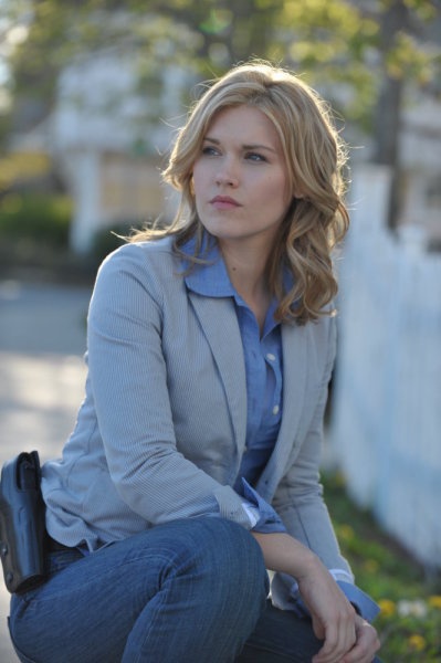 a woman is sitting on the curb with her hand in her pocket and looking off to the side