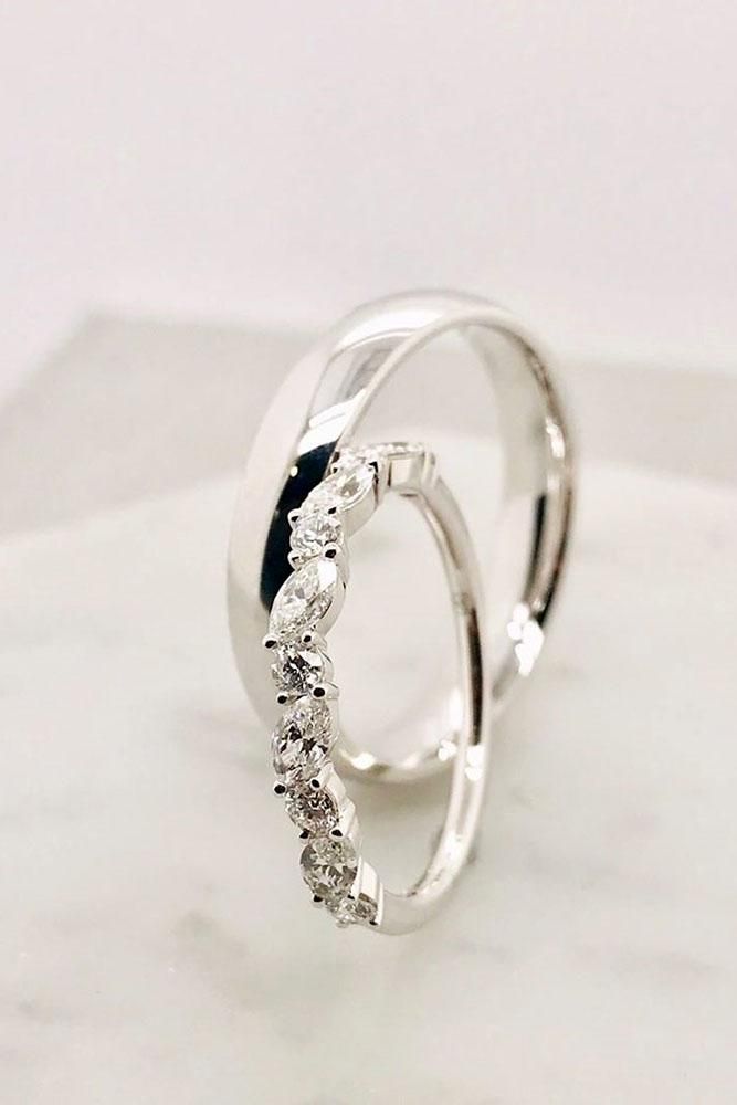 two white gold rings with diamonds on top of a marble slabd surface, one in the shape of a spiral