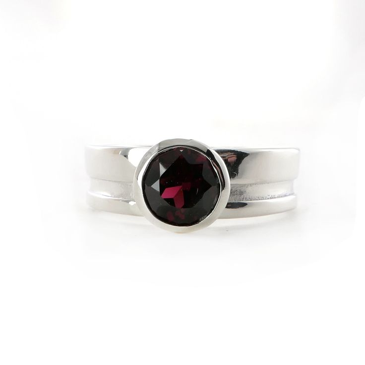 This gorgeous Garnet is set in a wide band with a cut out decorative element that goes all the way round the band. The same cut out also features on the bezel. The 6mm round Garnet is bezel set on a 6mm wide sterling silver band.The simplicity of this ring, matched with the sparkly red Garnet, makes it a perfect piece to add to your collection.I can add engraving to the inside of the ring, like a date, or name. It is an additional $20, if you would like this, please choose the personalization op Anniversary Ring With Bezel Setting And Wide Band, Formal Jewelry With Bezel Setting And Wide Band, Elegant Wide Band Sterling Silver Ring, Formal Wide Band Jewelry With Bezel Setting, Classic Jewelry With Bezel Setting And Wide Band, Classic Wide Band Jewelry With Tension Setting, Modern Ruby Ring With Bezel Setting, Modern Sterling Silver Jewelry With Bezel Setting, Formal Jewelry With Smooth Bezel And Round Band