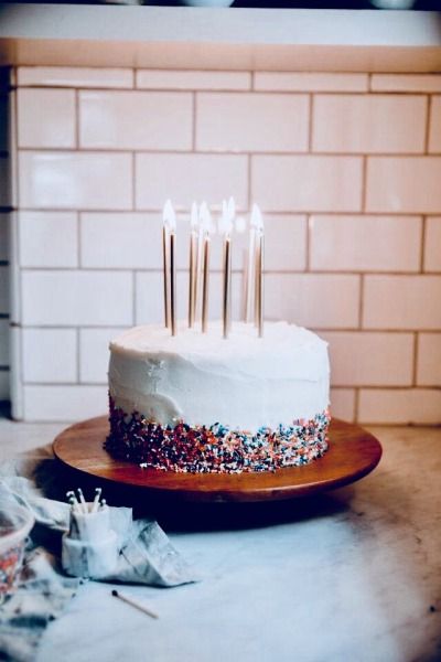 a white cake with sprinkles and lit candles