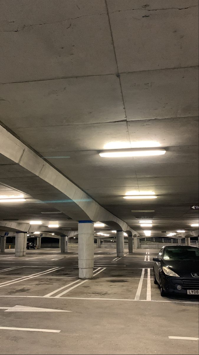 an empty parking garage with two cars parked in the lot and no one is there