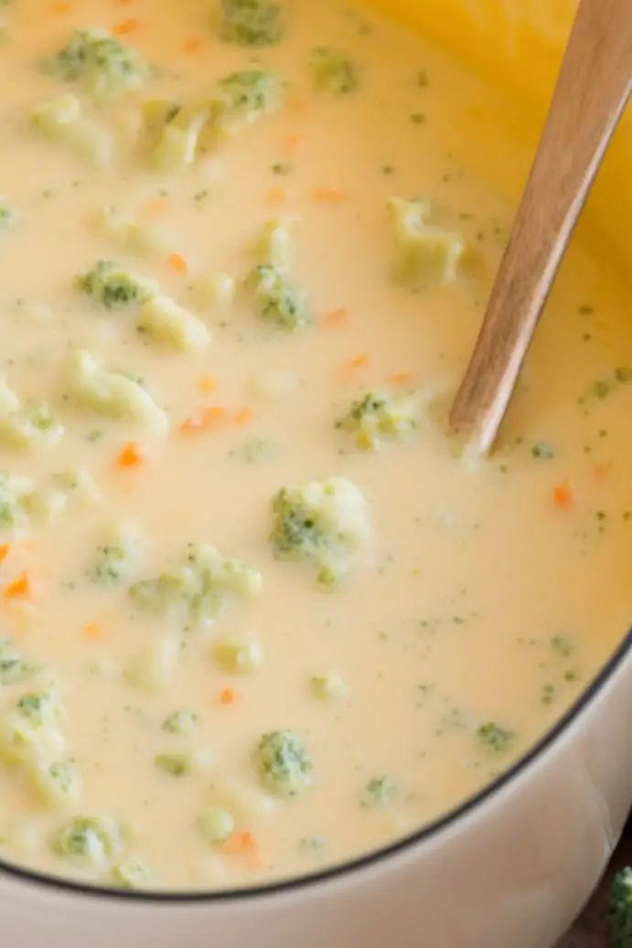 broccoli and cauliflower soup in a pot with a wooden spoon