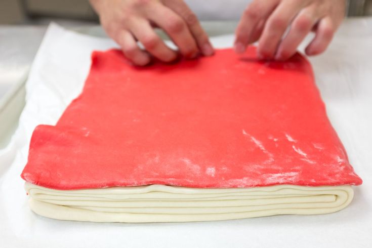 a person is kneading dough on top of a sheet of red wax paper